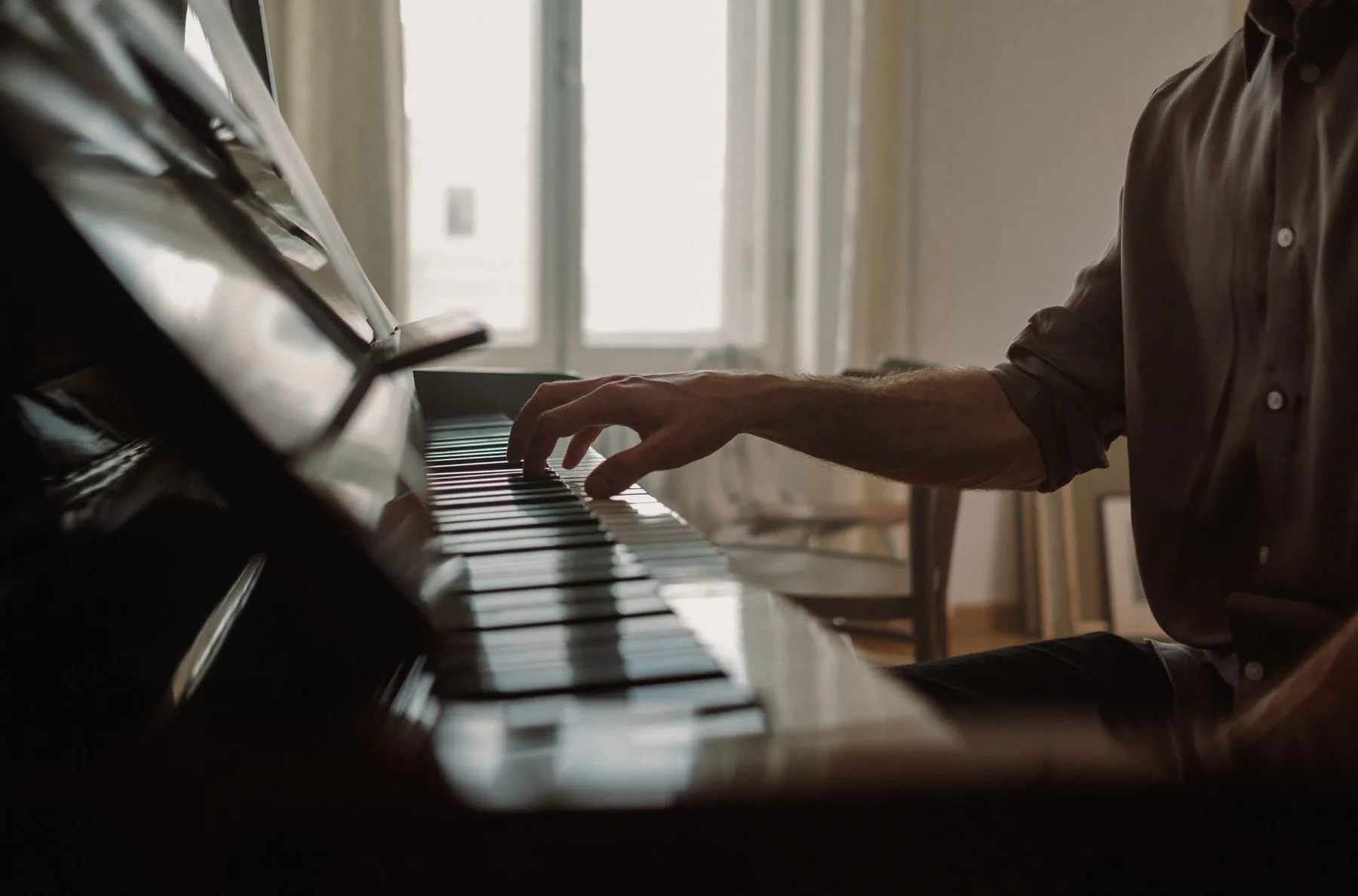 Pianiste jouant sur un piano près d’une fenêtre Pianiste jouant sur un piano près d’une fenêtre